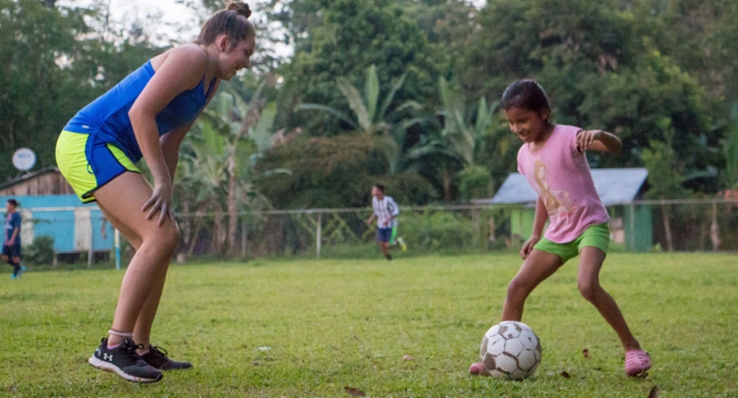 an adult plays soccer with a child